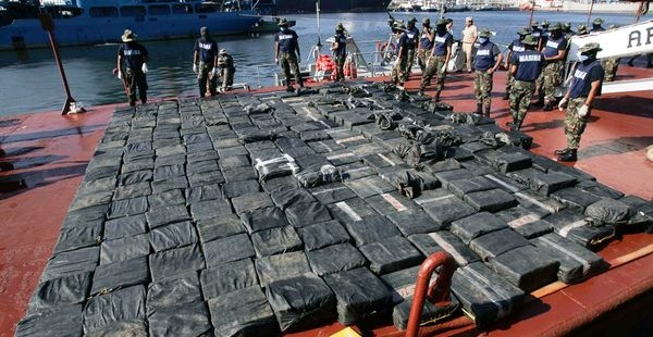 Sul ponte di una nave, centinaia di panetti di droga sequestrati allineati davanti a militari e agenti.
