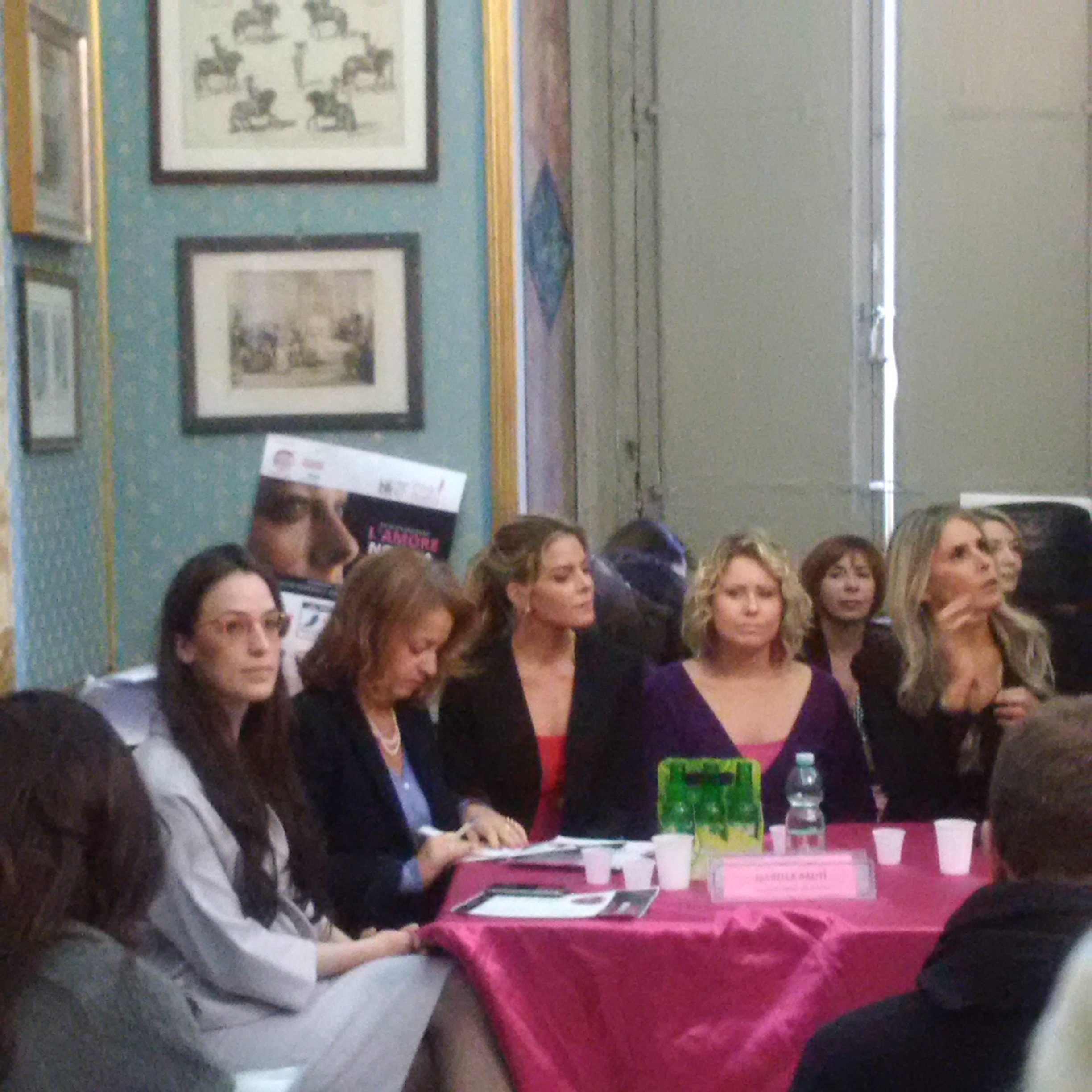Le relatrici sedute dietro un tavolo coperto di stoffa fucsia, in una sala storica.