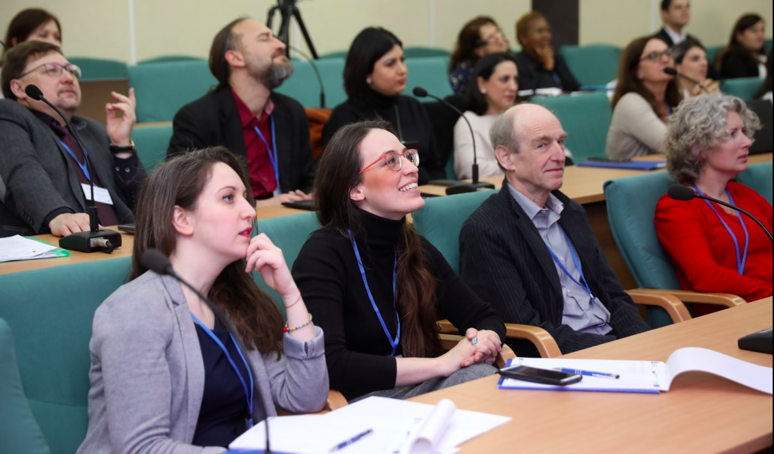 Il pubblico seduto ai banchi dell'aula durante un intervento, con i badge al collo.