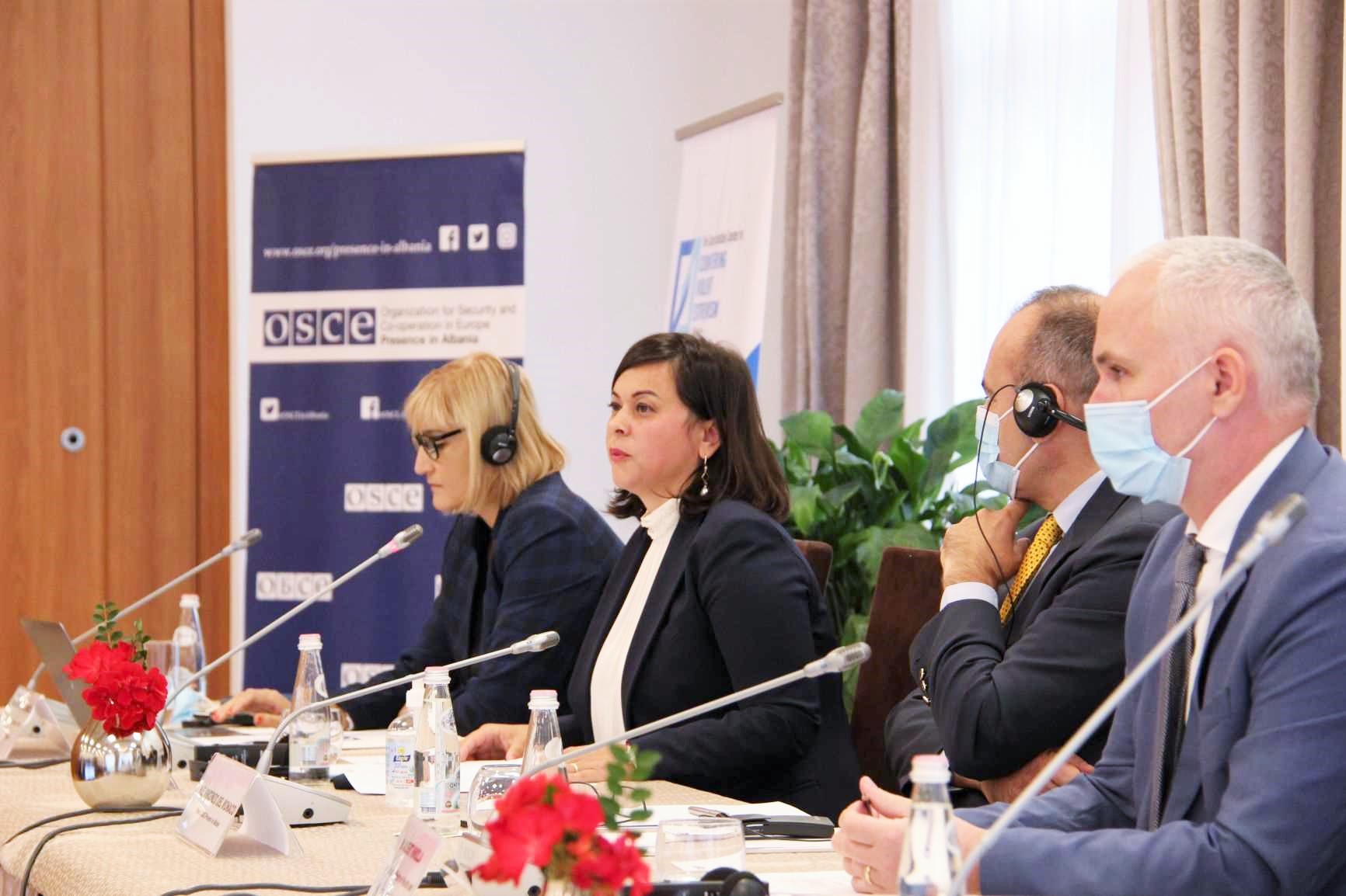 I relatori al tavolo con le cuffie per la traduzione, davanti al pannello dell'OSCE.