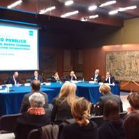 Il tavolo dei relatori davanti al pubblico, sotto la proiezione del titolo dell'incontro pubblico.