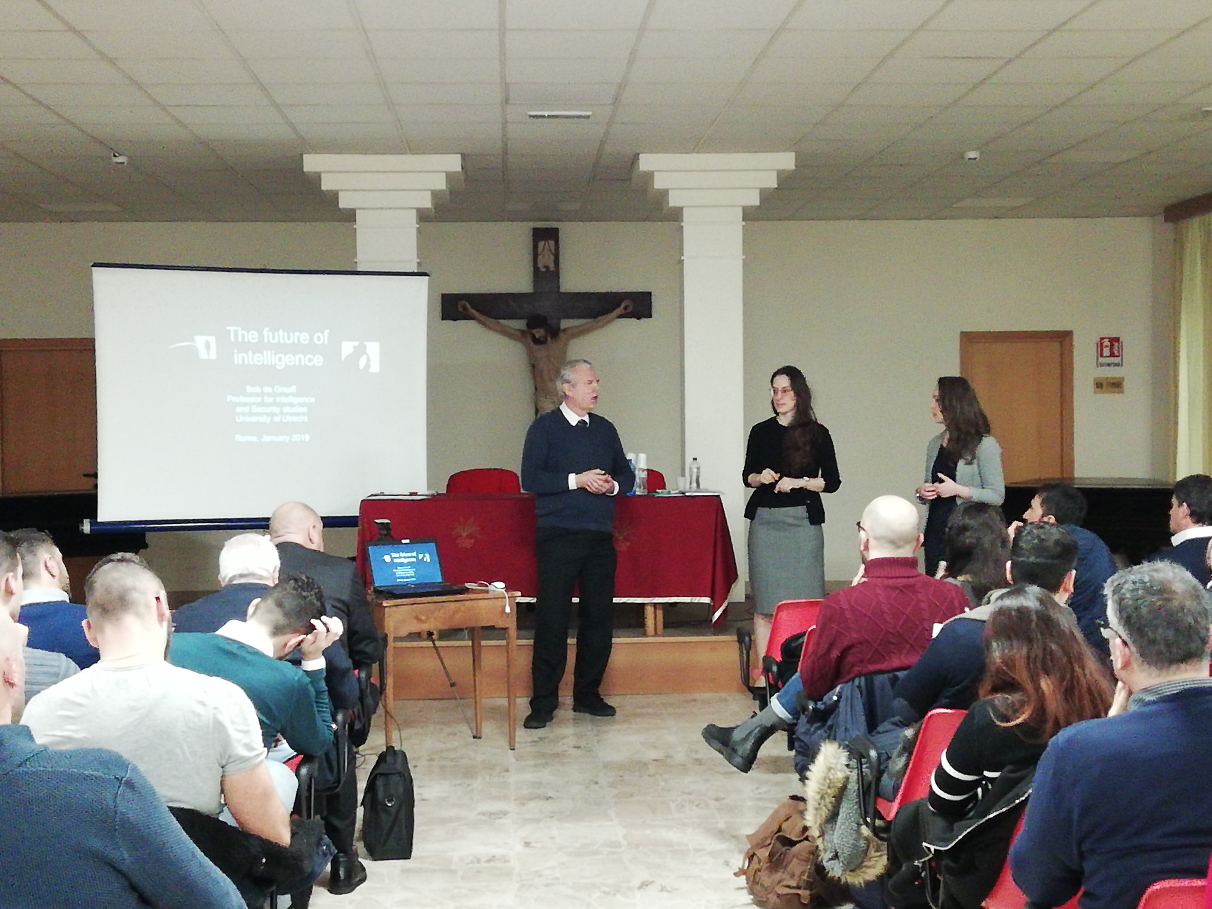 Un relatore e due relatrici davanti alla proiezione intitolata The future of intelligence.