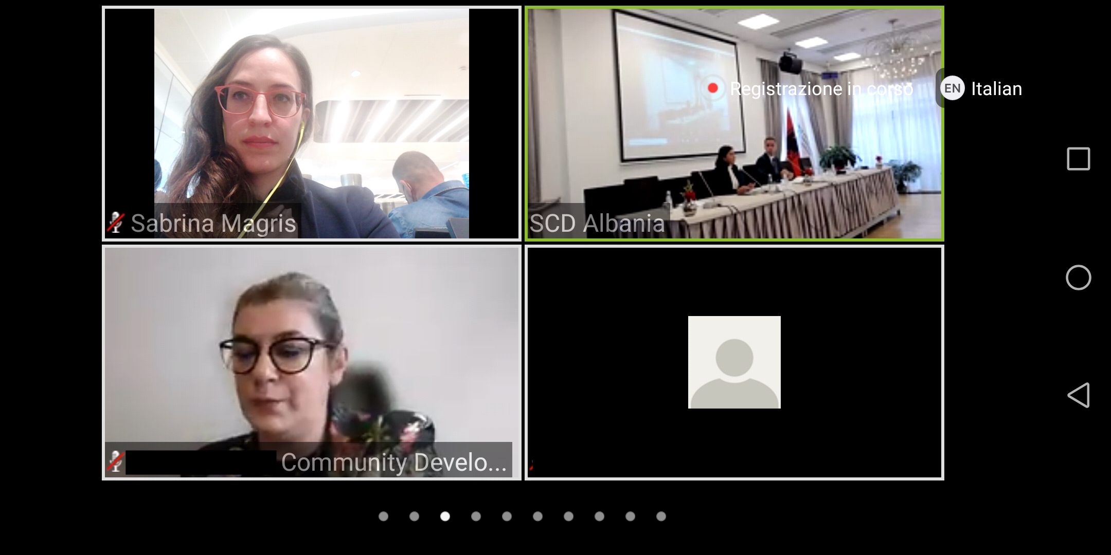 La schermata di un collegamento video con quattro riquadri: due relatrici, la sala della conferenza e un partecipante senza video.