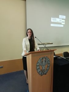 Una relatrice parla dal podio di un'aula universitaria, accanto allo schermo.