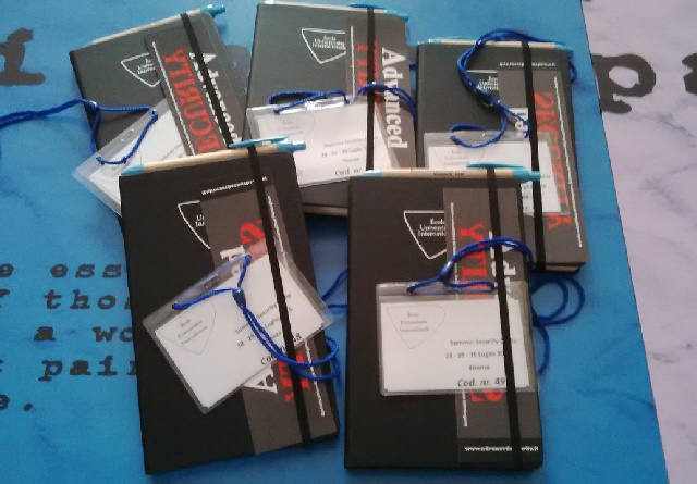 Il materiale dei partecipanti al Summer Security Camp: taccuini neri, badge e cordini blu.