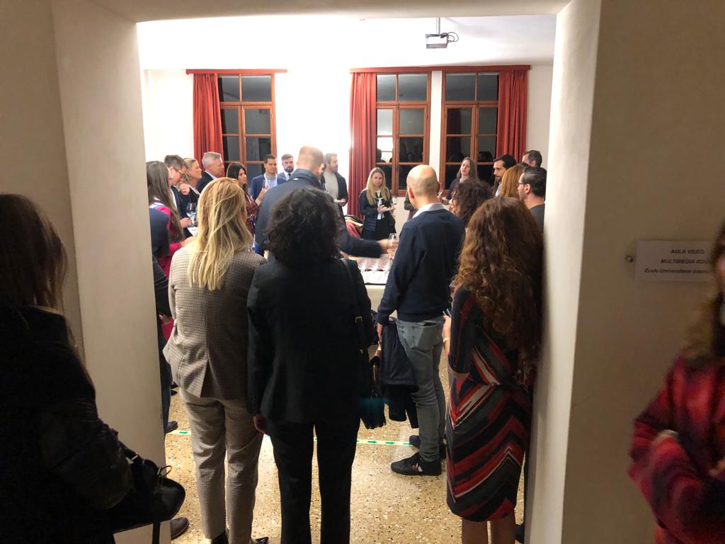 I partecipanti in piedi durante una pausa, visti dal vano di una porta.