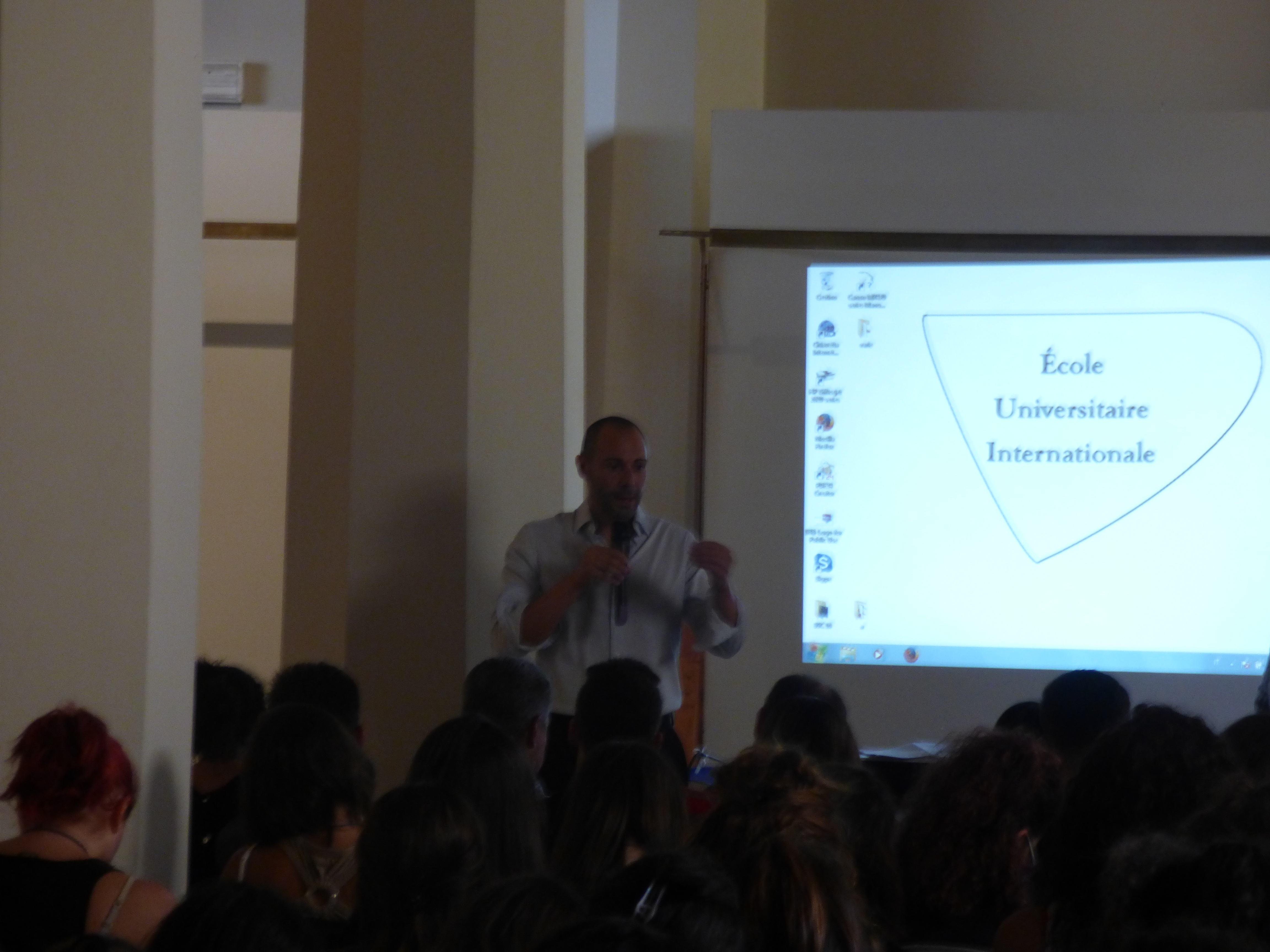 Un relatore davanti alla proiezione del logo di École Universitaire Internationale.