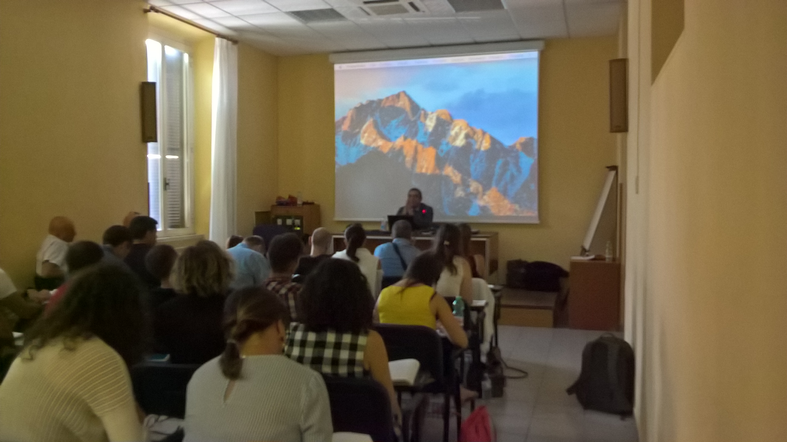 Il pubblico seduto davanti alla proiezione della fotografia di una montagna.