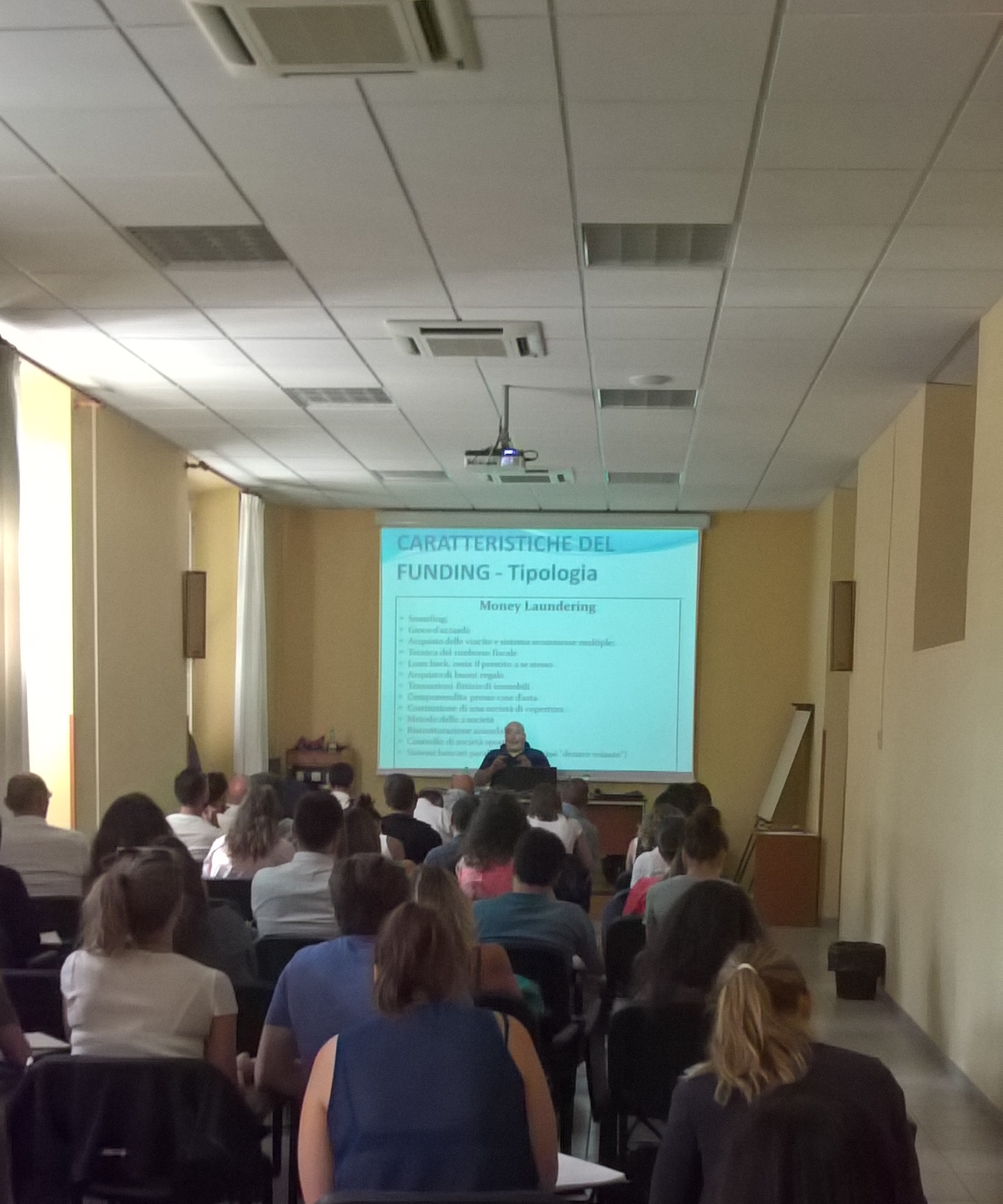 Un'aula piena davanti alla proiezione di una diapositiva sulle caratteristiche e le tipologie di finanziamento.