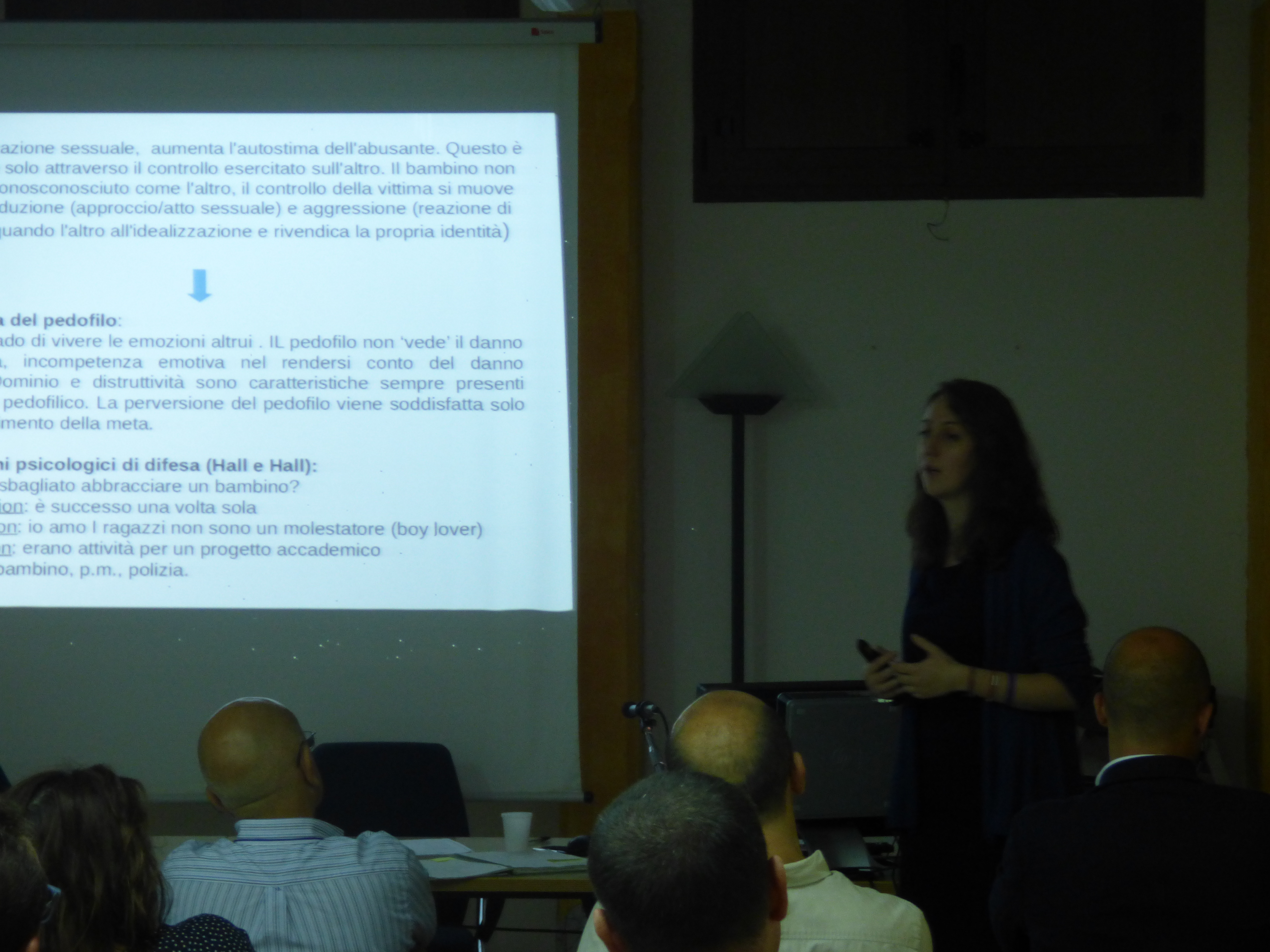 Una relatrice accanto alla proiezione di una diapositiva sui meccanismi psicologici di difesa.