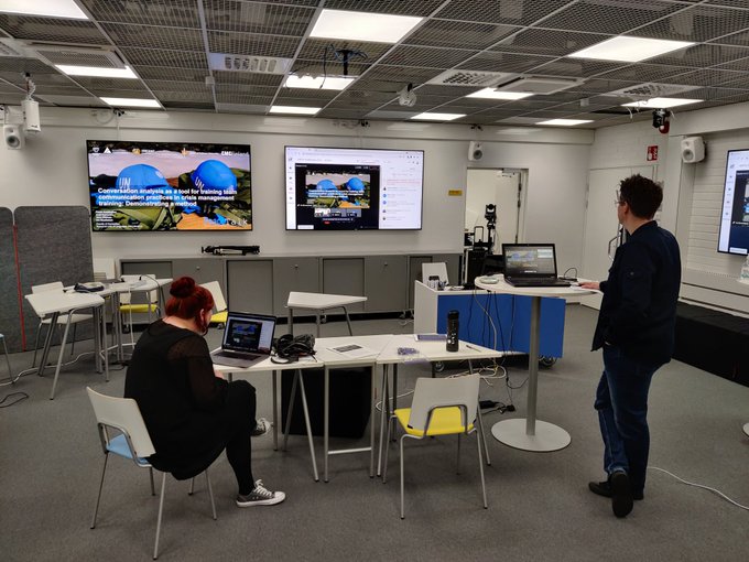 Uno studio di trasmissione con due schermi e le postazioni dei relatori, durante la conferenza in collegamento.