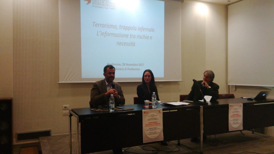 Il tavolo dei relatori visto di fronte, sotto la proiezione del titolo dell'incontro.