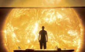 Una persona in controluce, in piedi davanti alla proiezione gigante del Sole.