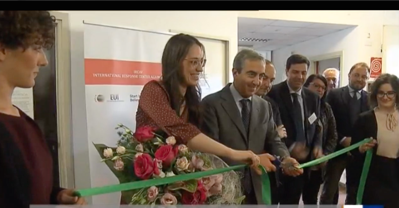 Il taglio del nastro verde all'inaugurazione, davanti ad alcune persone in piedi.