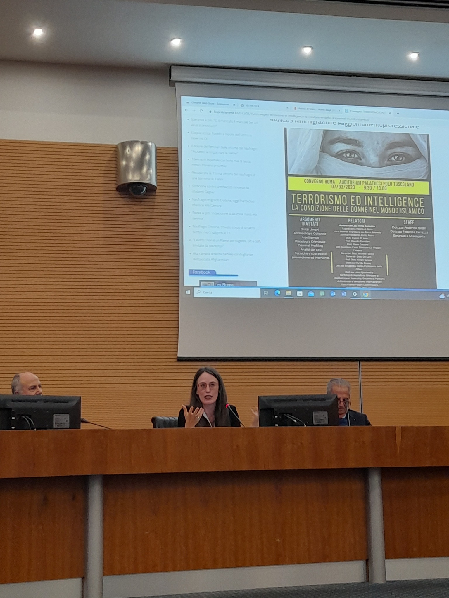 Una relatrice al banco fra due relatori, sotto la proiezione della locandina Terrorismo ed intelligence: la condizione delle donne nel mondo islamico.