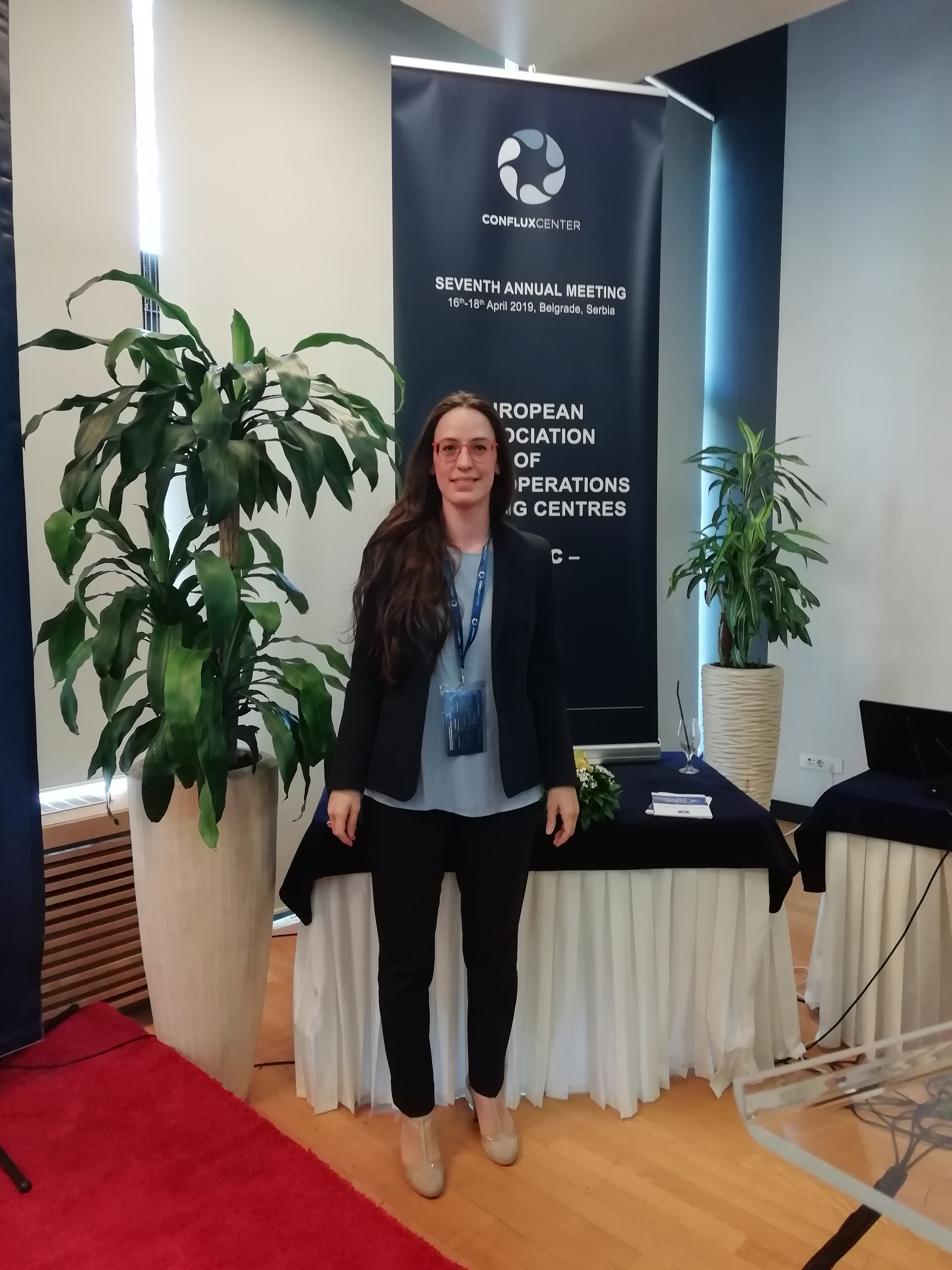 Una partecipante in posa davanti al banner del settimo incontro annuale della European Association of Peace Operations Centres, Belgrado 2019.
